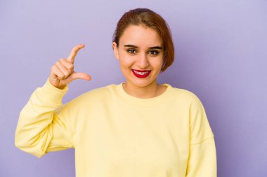 Genç Arap melez kadın işaret parmağıyla küçük bir şey tutuyor, gülümsüyor ve kendinden emin..