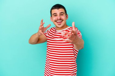 Mavi arka planda izole edilmiş genç beyaz adam kameraya sarıldığı için kendinden emin hissediyor..