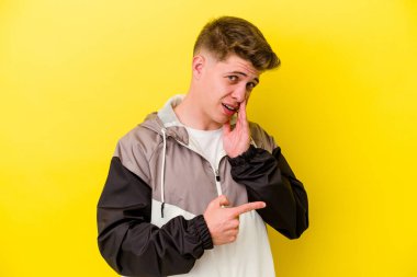 Sarı arka planda izole edilmiş genç beyaz bir adam bir dedikodu söylüyor, bir haber sunuyor..