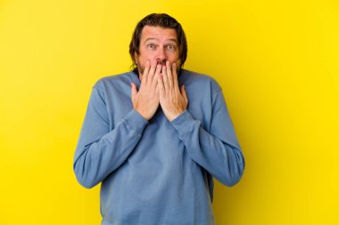 Sarı arka planda izole edilmiş orta yaşlı beyaz bir adam şok geçirmiş, ağzı ellerle kaplanmış, yeni bir şey keşfetmeye hevesli..