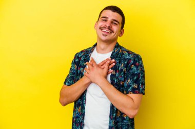 Sarı arka planda izole edilmiş beyaz bir genç, dost canlısı bir ifadeye sahip, avuçlarını göğsüne bastırıyor. Aşk konsepti.