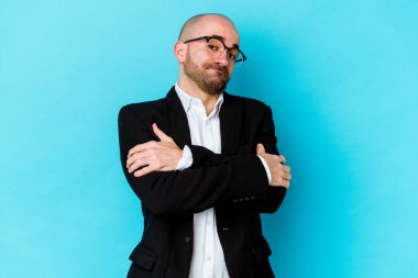 Genç, beyaz, kel bir adam mavi arka planda izole edilmiş, güler yüzlü ve mutlu..