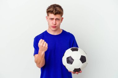 Arka planda izole bir şekilde futbol oynayan genç beyaz adam yumruğunu kameraya gösteriyor, agresif bir yüz ifadesi var..