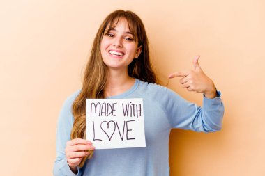 Genç, beyaz bir kadın elinde aşk levhasıyla izole edilmiş, gömlek fotokopi odasını gösteren gururlu ve kendinden emin birini tutuyor.