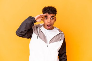 Genç Afro-Amerikalı kıvırcık adam mor renkte izole edilmiş yüksek sesle bağırıyor, gözlerini açık ve ellerini gergin tutuyor.