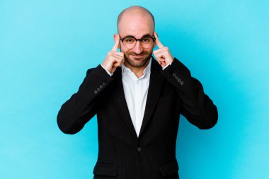 Kafkas kökenli genç bir adam mavi arka planda izole edilmiş vazifesine odaklanmış, parmaklarını işaret ediyor..