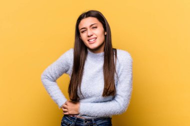 Sarı arka planda izole edilmiş genç bir Hintli kadın. Karaciğer ağrısı, mide ağrısı var..