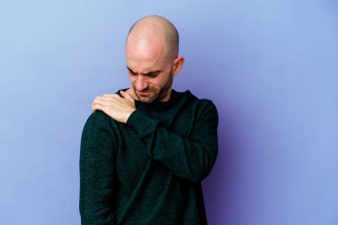 Mor arka planda izole edilmiş, omuz ağrısı olan genç, beyaz kel bir adam..