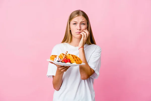 年轻的俄罗斯女人吃着华夫饼 孤立地咬着指甲 紧张而焦虑 — 图库照片