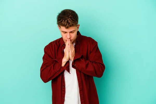 Kafkasyalı Genç Adam Mavi Arka Planda Izole Edilmiş Dua Ediyor — Stok fotoğraf