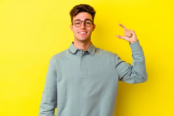 Young Caucasian Man Isolated Yellow Background Holding Something Little Forefingers — Stock Photo, Image