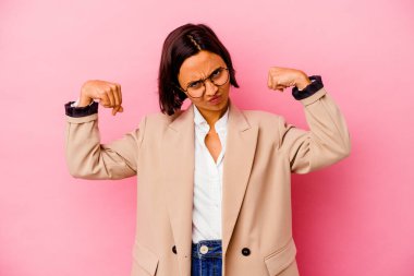 Pembe arka planda izole edilmiş genç bir iş kadını güçlü bir jest yapıyor, kadınsı gücün sembolü.