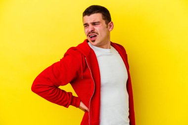 Sarı arka planda izole edilmiş beyaz bir adam sırt ağrısı çekiyor..