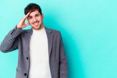 Mavi arka planda izole edilmiş genç beyaz adam yüksek sesle bağırıyor, gözleri açık ve elleri gergin tutuyor..