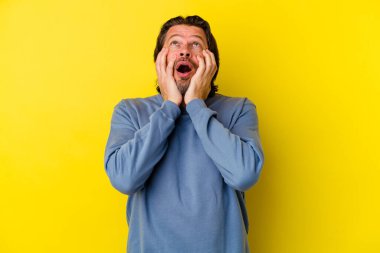 Orta yaşlı, beyaz bir adam sarı arka planda izole edilmiş sızlanıyor ve ağlıyordu..