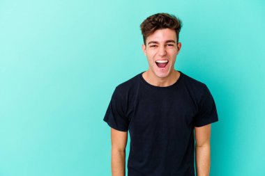 Kafkasyalı genç adam mavi arka planda izole edilmiş. Çok kızgın, öfkeli, hayal kırıklığına uğramış..