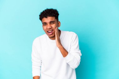 Genç Afro-Amerikalı kıvırcık adam mavi üzerine izole edilmiş güçlü bir diş ağrısı, azıdişi ağrısı var..