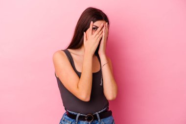 Pembe arka planda izole edilmiş genç beyaz kadın parmaklarıyla gözünü kırp korkmuş ve gergin..