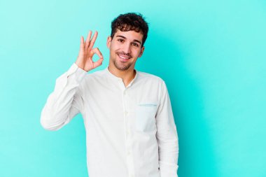 Kafkasyalı genç adam mavi arka planda izole edilmiş neşeli ve kendinden emin..