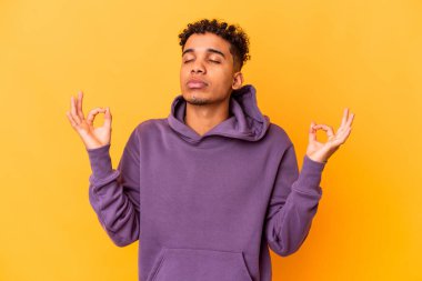 Genç Afro-Amerikalı kıvırcık adam, yoğun bir günün ardından mora bürünmüş, yoga yapıyor..