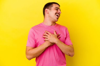 Sarı arka planda izole edilmiş beyaz bir adam. Gülüyor, elini yüreğine koyuyor, mutluluk kavramını koruyor..