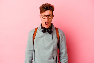 Pembe arka planda izole edilmiş genç bir öğrenci çok sinirli ve agresif çığlıklar atıyor..