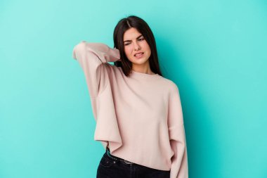 Mavi arka planda izole edilmiş genç beyaz kadın yorgun ve uykulu ellerini başının üstünde tutuyor..