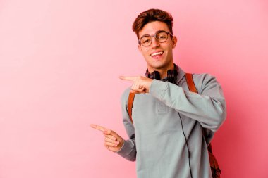 Pembe arka planda izole olmuş genç bir öğrenci işaret parmağıyla işaret ederek heyecanlanıyor..