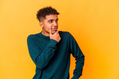 Genç Afro-Amerikan kıvırcık adamı, mor renkte izole edilmiş, kuşkulu ve kuşkulu bir ifadeyle yana bakıyor..