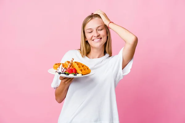 Joven Rusa Comiendo Waffle Aislado Ríe Alegremente Manteniendo Las Manos —  Fotos de Stock