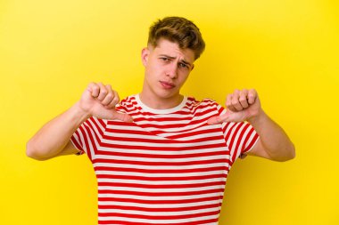 Sarı arka planda izole edilmiş, hoşlanmadığı bir hareket gösteren beyaz bir genç. Anlaşmazlık konsepti.