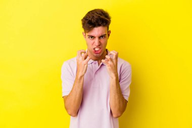 Sarı arka planda izole edilmiş genç beyaz adam gergin elleriyle çığlık atıyor..