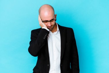 Genç, beyaz, kel bir adam mavi arka planda izole edilmiş. Sıkılmış, yorgun ve dinlenmeye ihtiyacı var..