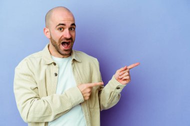 Mor arka planda izole edilmiş beyaz saçlı genç adam işaret parmağıyla işaret ederek heyecanlanıyor..