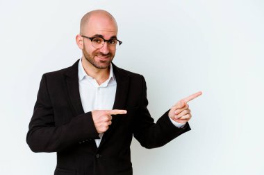 Genç beyaz tenli kel adam mavi arka planda izole edildi. İşaret parmağıyla fotokopi alanını işaret ederek şok oldu..