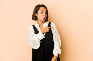 Genç İspanyol kadın kendini izole edip gülümsüyor ve boş alanda bir şeyler gösteriyor..