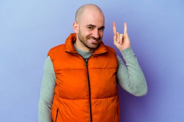 Mor arka planda izole edilmiş beyaz kel bir adam boynuzlarını devrim konsepti olarak gösteriyor..