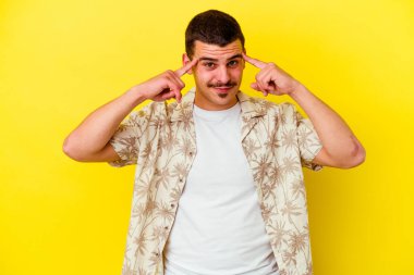 Sarı arka planda izole genç beyaz adam bir göreve odaklanmış, işaret parmaklarını işaret ediyor.