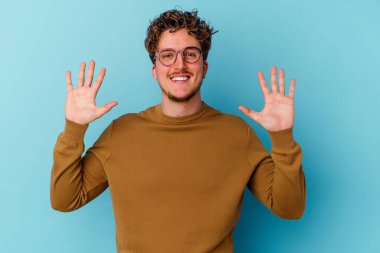 Mavi arka planda gözlüklü genç beyaz adam 10 numarayı elleriyle gösteriyor..