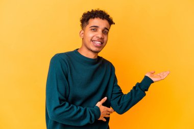 Genç Afro-Amerikalı kıvırcık adam mor üzerine izole edilmiş bir şekilde bir avuç içinde fotokopi alanı gösteriyor ve belinde bir el daha tutuyor..