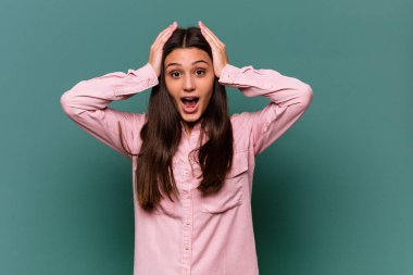 Genç Hintli kadın mavi arka planda izole edilmiş bağırıyor, çok heyecanlı, tutkulu, bir şeyden memnun..