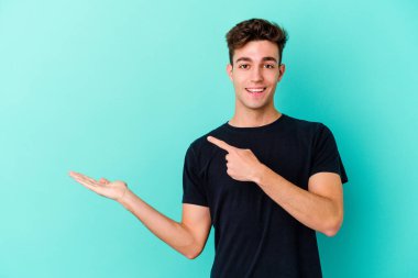 Kafkasyalı genç adam mavi arka planda izole edilmiş. Elinde palmiye ağacının bir kopyası olduğu için heyecanlı..