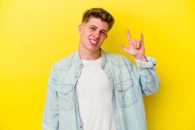 Sarı arka planda izole edilmiş genç beyaz adam boynuzlarını devrim konsepti olarak gösteriyor..