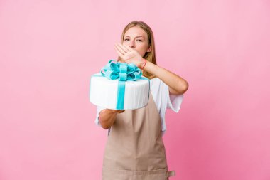 Genç Rus fırıncı kadın elinde lezzetli bir pasta ile inkar jesti yapıyor.