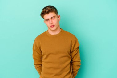 Kafkasyalı genç adam mavi arka planda izole edilmiş üzgün, ciddi yüzlü, mutsuz ve hoşnutsuz..