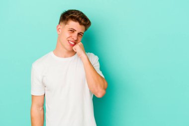 Mavi arka planda izole edilmiş genç beyaz adam rahatlamış bir şeyin fotokopi odasına baktığını düşünüyor..