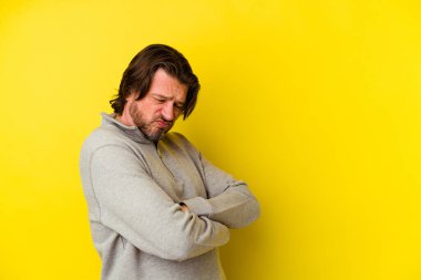 Sarı arka planda izole edilmiş orta yaşlı beyaz adam tekrarlanan bir görevden bıktı..