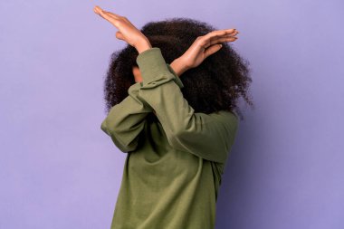 Genç Afro-Amerikalı kıvırcık kadın mor arka planda izole edilmiş iki kolu çapraz tutuyor, inkar kavramı.