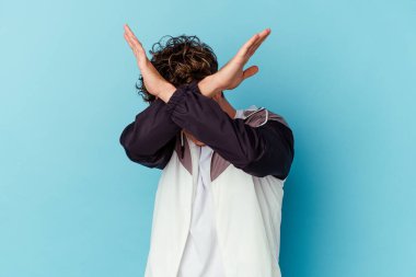 Mavi arka planda gözlüklü genç beyaz adam iki kolu çapraz tutuyor, inkar kavramı..