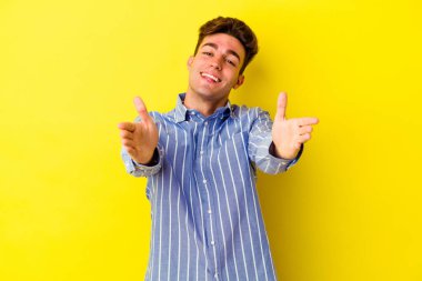 Sarı arka planda izole edilmiş genç beyaz adam kameraya sarıldığı için kendinden emin hissediyor..